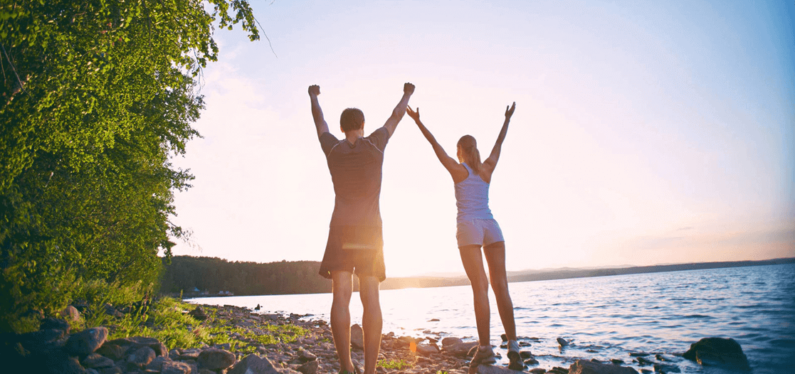 Couple standing at beach with arms raised in victory
